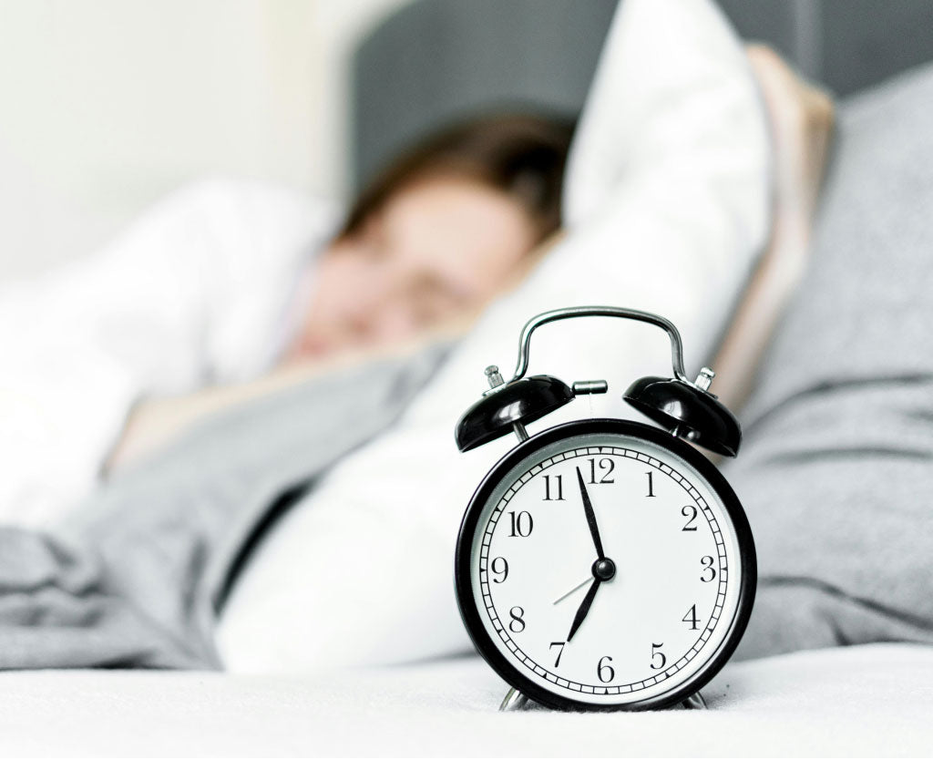 Alarm Clock On Side Table Next To Someone Sleeping