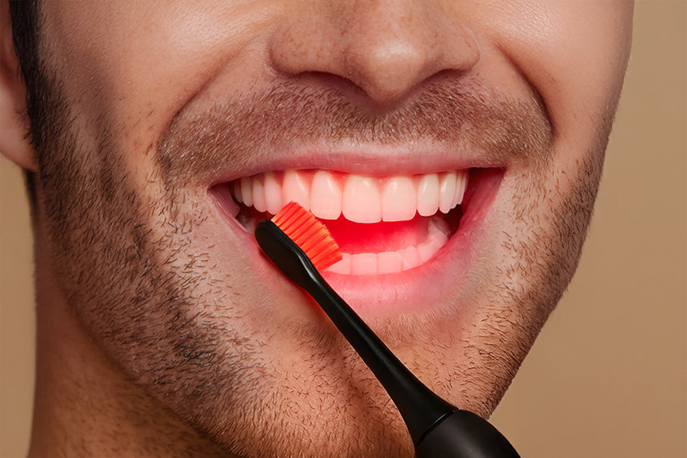 Close-up of a person using an electric toothbrush with a red bristle head.